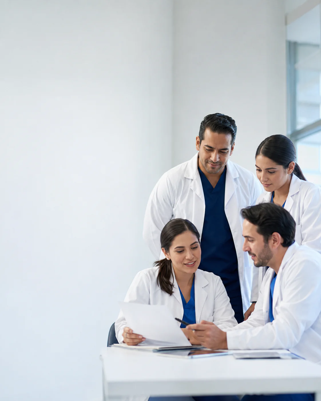 Grupo de profesionales de la salud conversando alrededor de una mesa de trabajo.